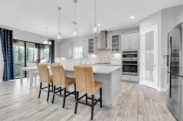 a kitchen with stainless steel appliances kitchen island granite countertop a dining table chairs and white cabinets