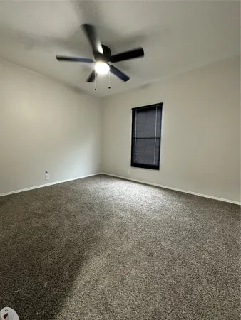 an empty room with a ceiling fan and a window