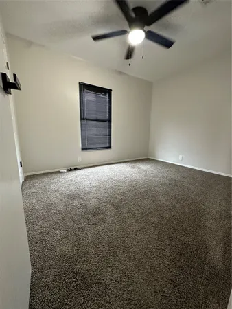 an empty room with a ceiling fan and a window
