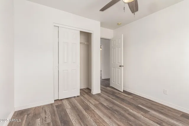 an empty room with closet and a ceiling fan