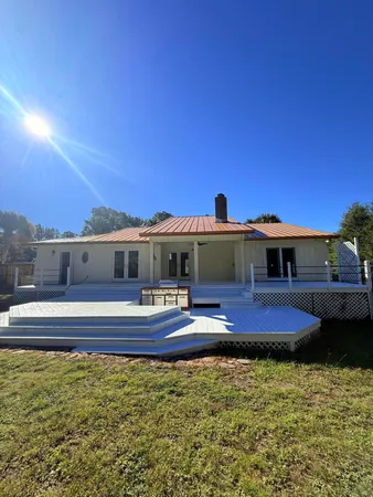 a view of a house with a big yard and large trees