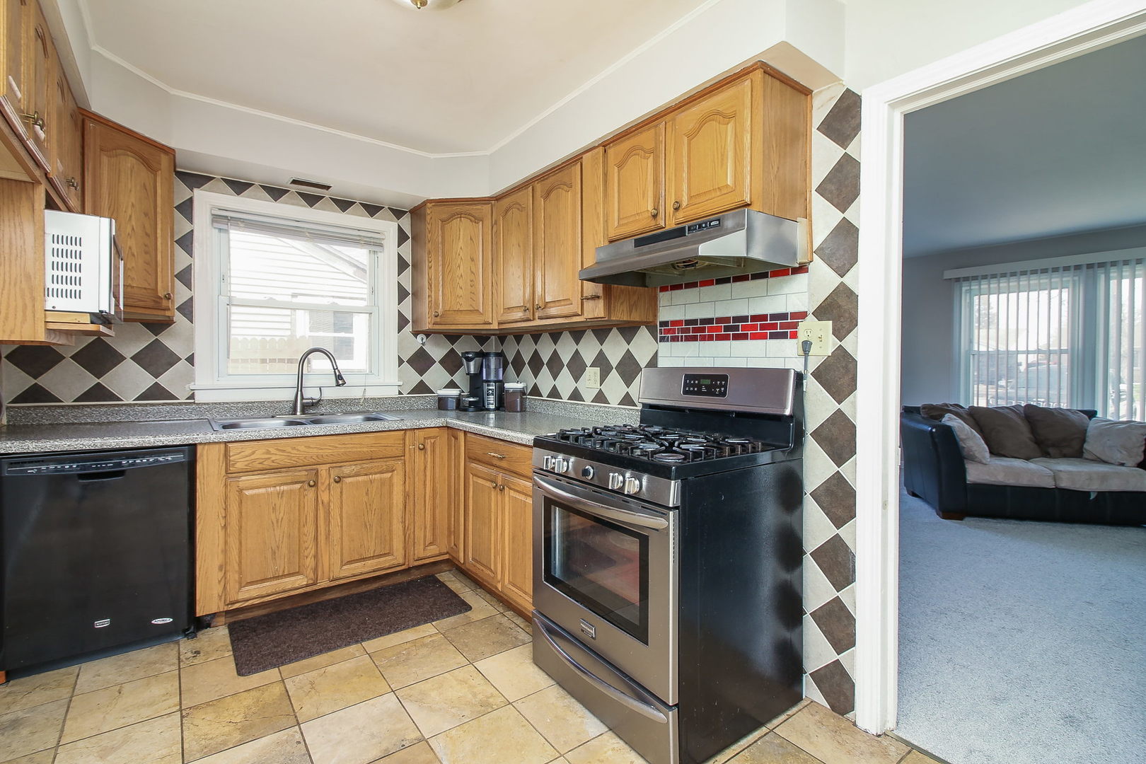 1128 South Wolf Road Des Plaines, IL 60016 - Photo 4 of 20 a kitchen with stainless steel appliances granite countertop a stove a sink and a microwave