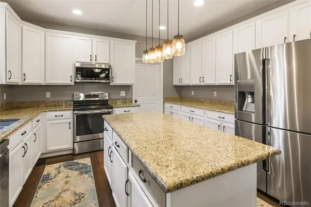a kitchen with kitchen island granite countertop stainless steel appliances a stove refrigerator sink and cabinets