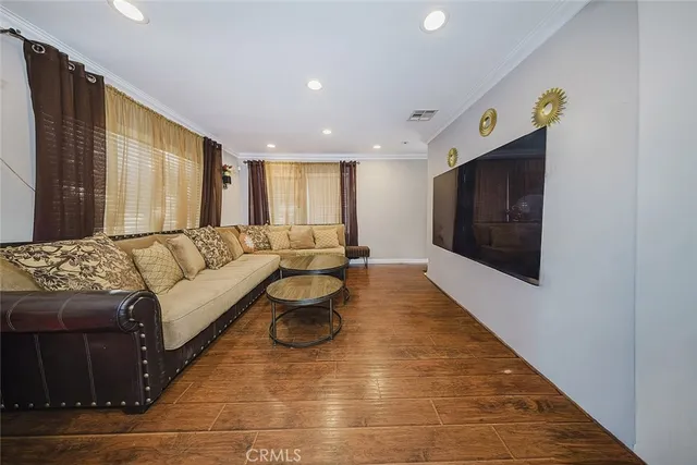 a living room with couches and kitchen view with wooden floor