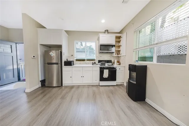 a kitchen with stainless steel appliances a refrigerator and wooden floor