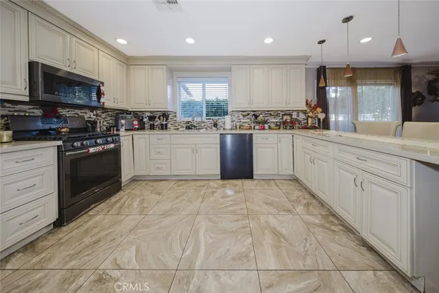 a kitchen with stainless steel appliances granite countertop a stove top oven a sink dishwasher and a refrigerator
