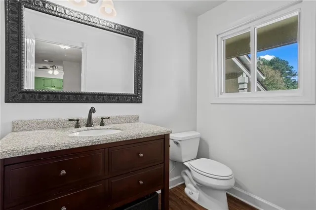 a bathroom with a granite countertop toilet a sink and mirror