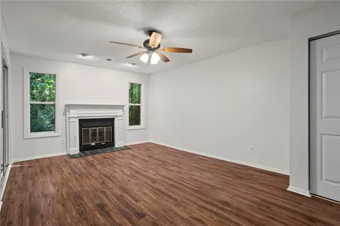 a view of an empty room with wooden floor fireplace and a window