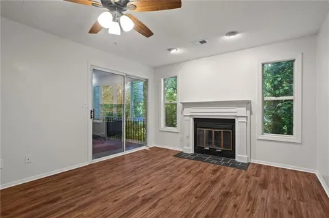 a view of an empty room with wooden floor fireplace and a window