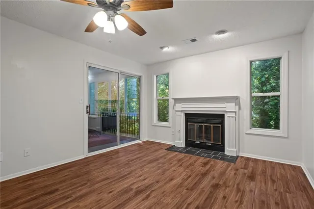 a view of an empty room with wooden floor fireplace and a window
