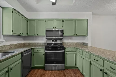 a kitchen with granite countertop a sink a stove and cabinets
