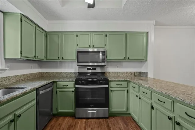 a kitchen with granite countertop a sink a stove and cabinets
