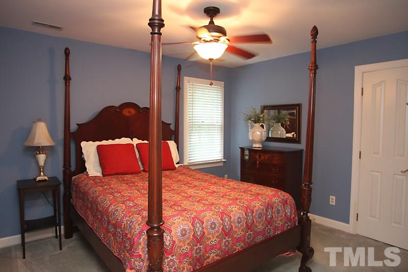 12301 Staunton Court Raleigh, NC 27613 - Photo 15 of 25 a bedroom with a bed and a chandelier