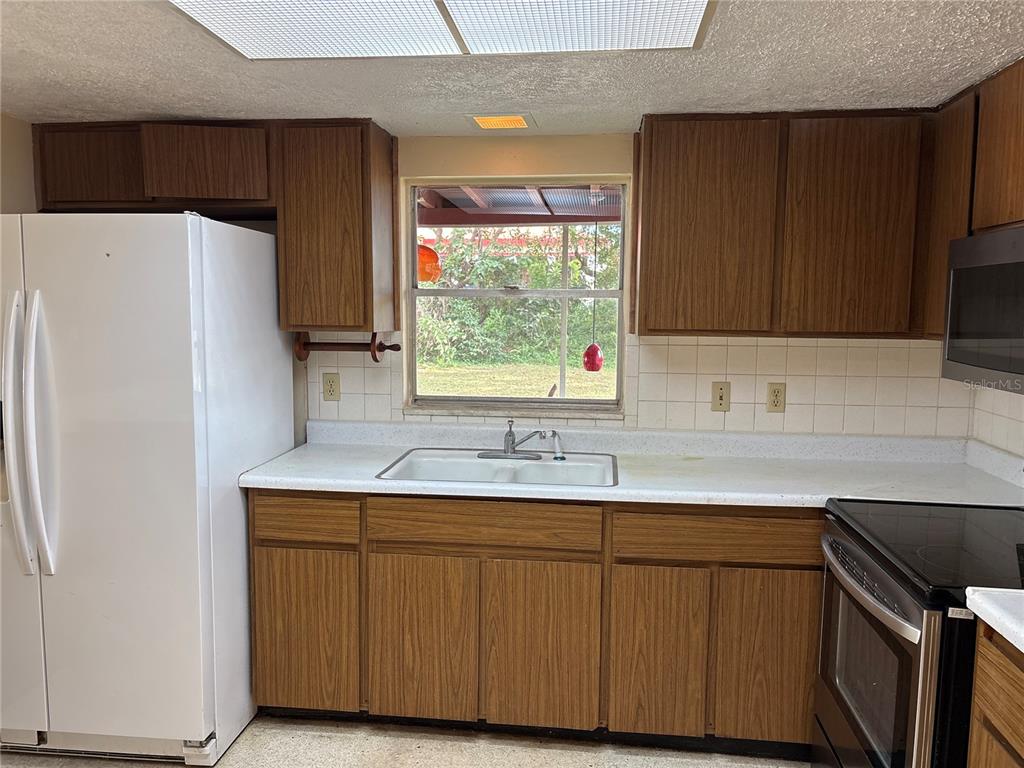 5107 East 120th Avenue Temple Terrace, FL 33617 - Photo 3 of 24 a kitchen with a sink a refrigerator and window