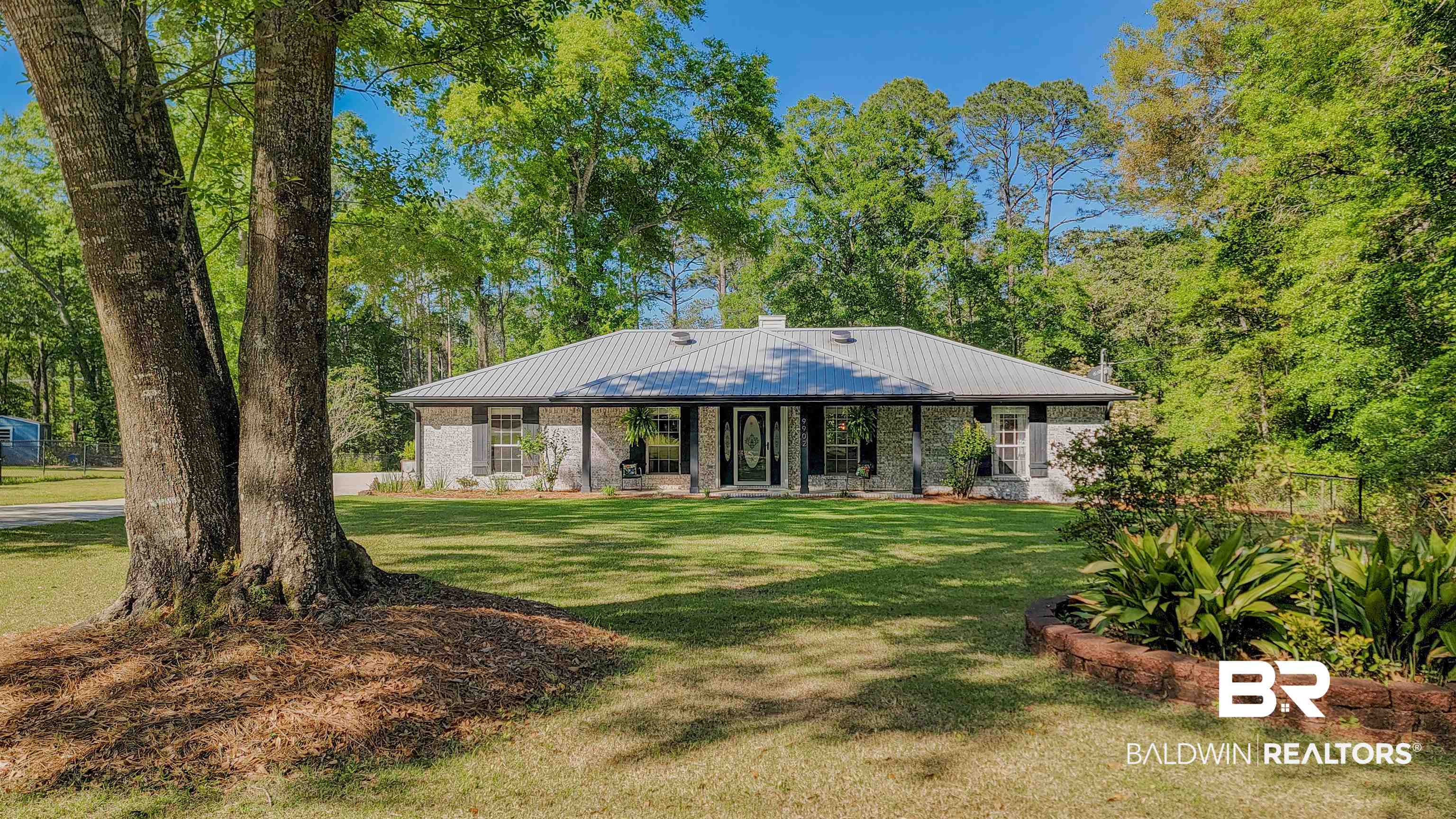 Rear view of house with covered porch, a yard, metal roof, and fence