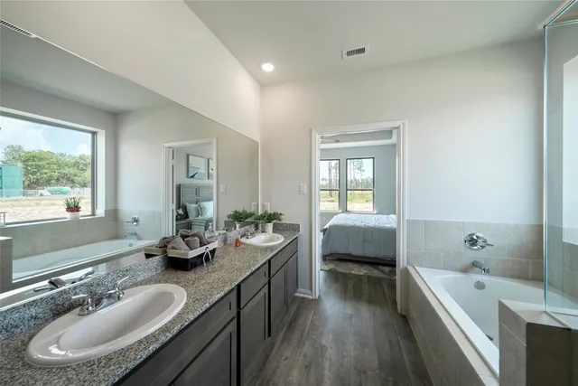a bathroom with a granite countertop tub sink and glass door