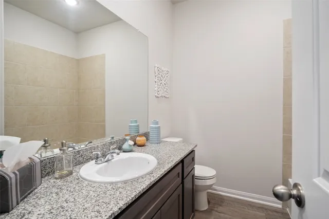 a bathroom with a granite countertop sink a toilet and a mirror