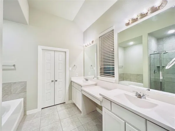 a bathroom with a granite countertop double vanity sink a mirror and a bathtub