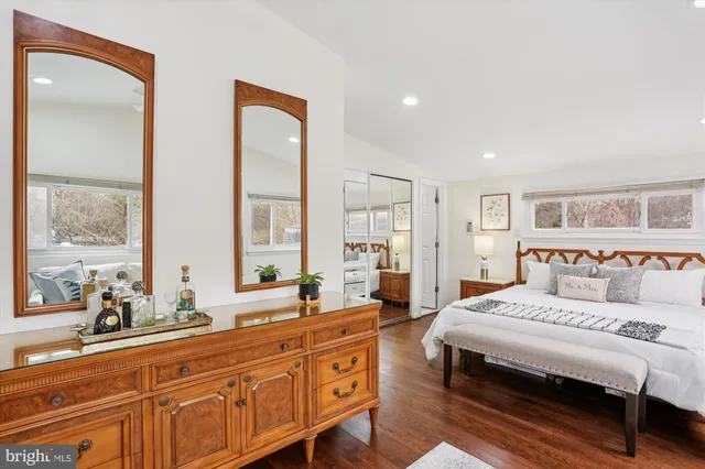 a spacious bedroom with a bed a large window and potted plant on the dresser