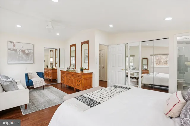 a bedroom with a bed couch and wooden floor