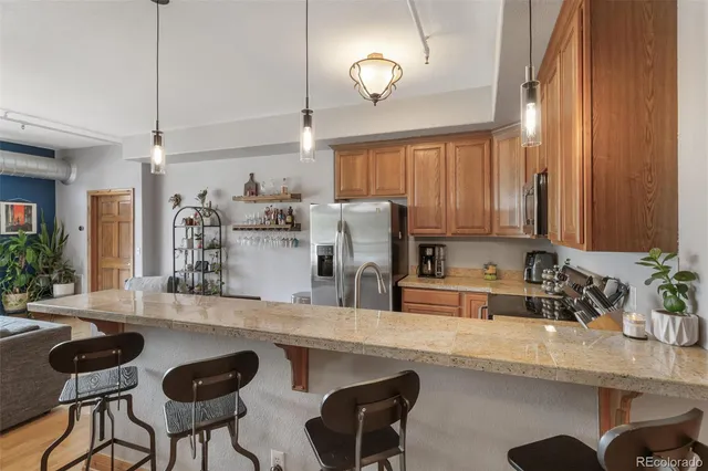 a kitchen with stainless steel appliances granite countertop a refrigerator a stove and a sink with wooden floor