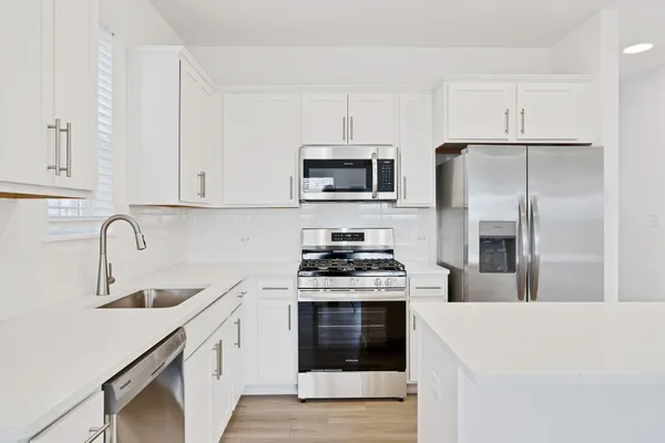 a kitchen with stainless steel appliances a stove a sink a refrigerator and cabinets