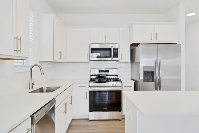 a kitchen with stainless steel appliances a stove a sink a refrigerator and cabinets