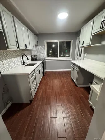 a large kitchen with a sink and wooden floor