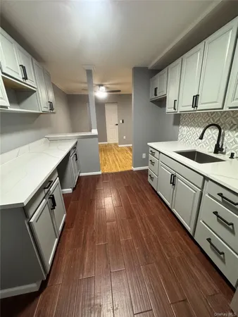 a kitchen with stainless steel appliances granite countertop a sink a stove and white cabinets with wooden floor