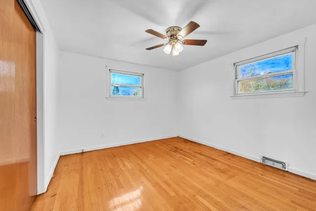 a view of an empty room with wooden floor and closet
