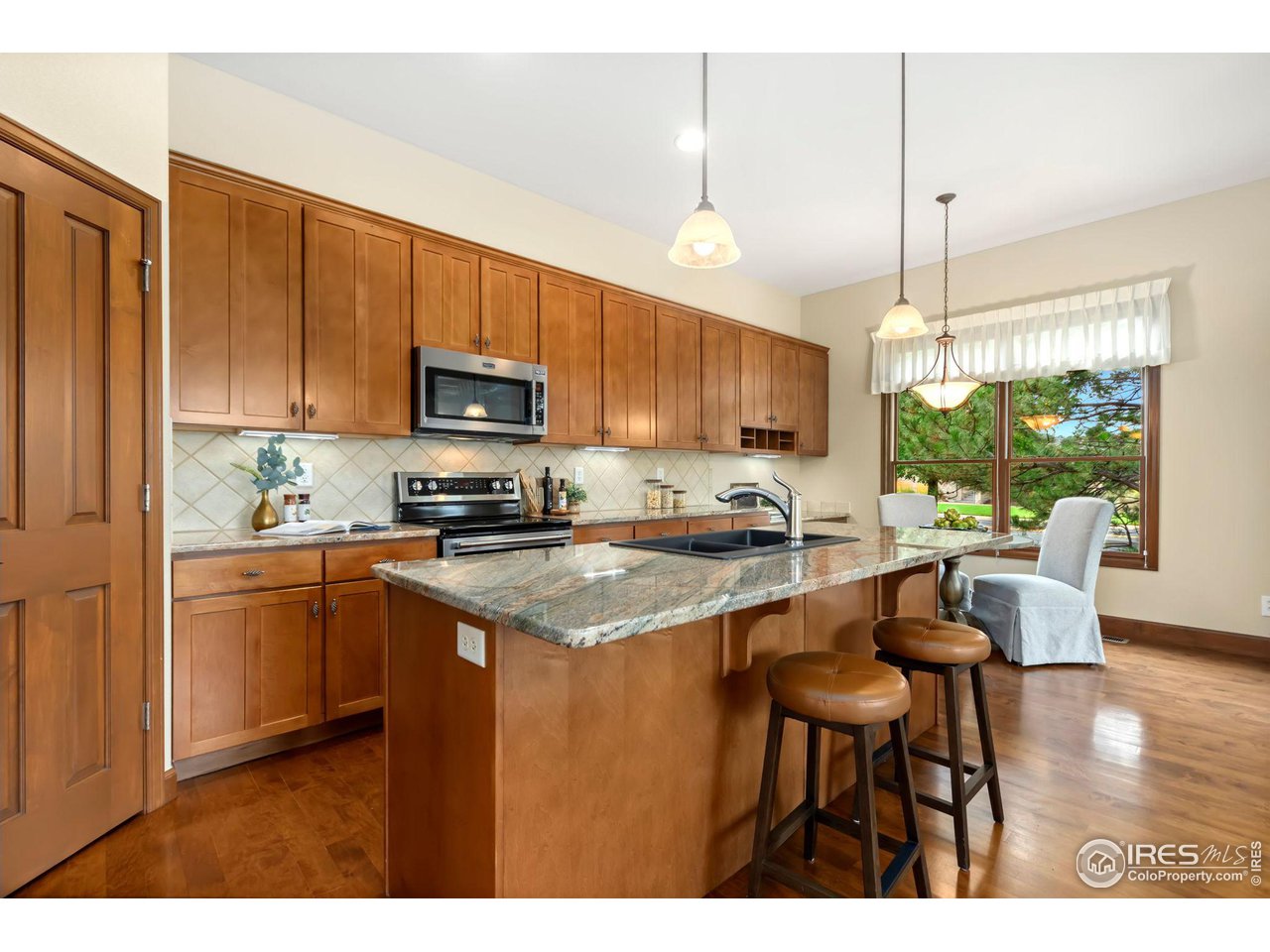 8209 Spinnaker Bay Drive Windsor, CO 80528 - Photo 9 of 26 a kitchen with stainless steel appliances granite countertop a stove a sink dishwasher a microwave oven with cabinets and wooden floor