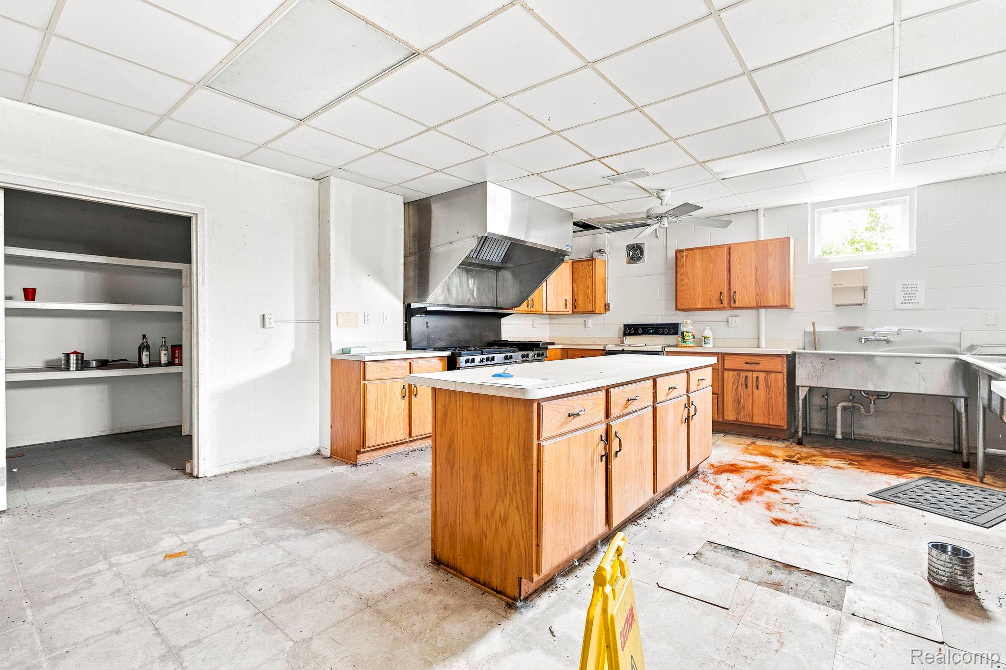9735 Dolan Road Columbus, MI 48063 - Photo 57 of 63 Spacious kitchen featuring a large central island, wood-finish cabinetry, a commercial-style range hood, ample counter space, and a stainless steel utility sink