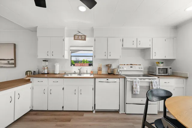 a kitchen with granite countertop white cabinets and white appliances