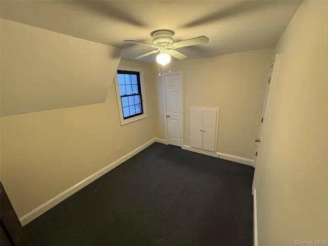 an empty room with a fan & a window