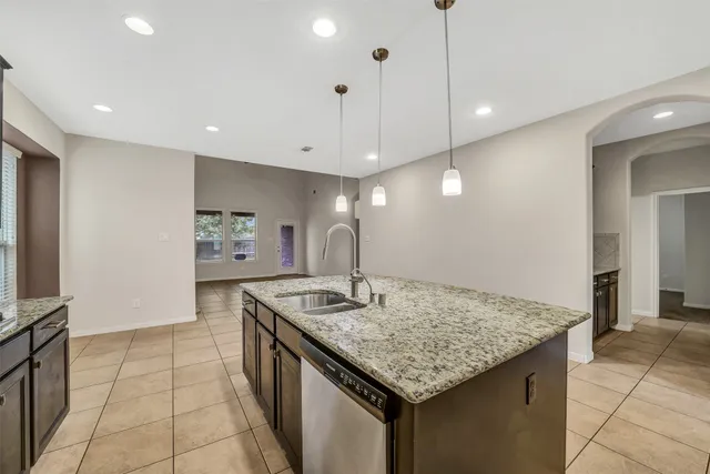 a kitchen with kitchen island granite countertop a stove a sink a counter top space and cabinets