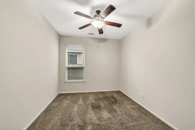 an empty room with ceiling fan and window
