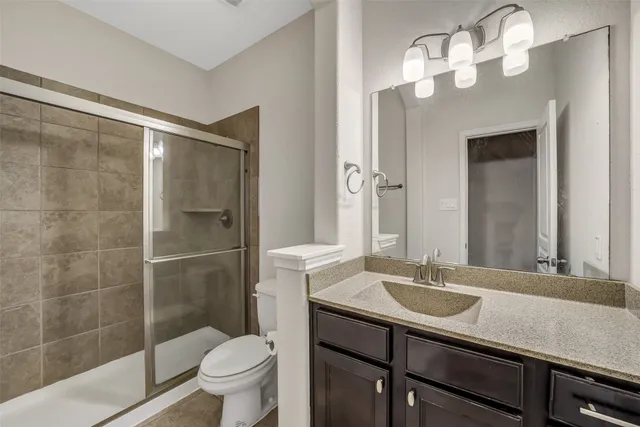 a bathroom with a sink a toilet a mirror and shower