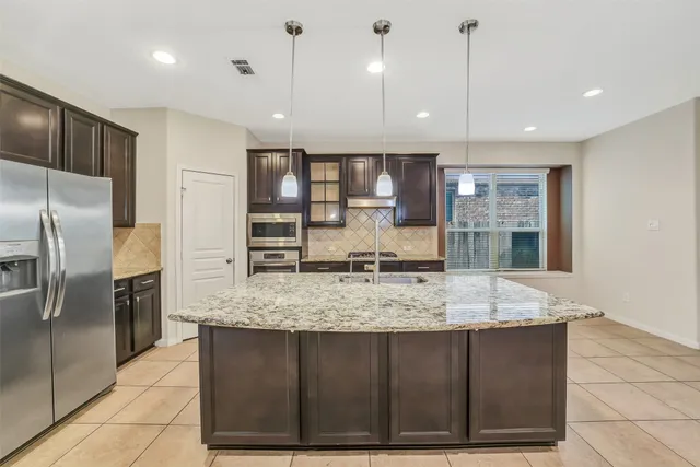 a kitchen with kitchen island granite countertop a large counter top stainless steel appliances and cabinets