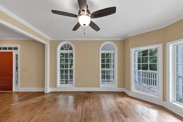 a view of an empty room with wooden floor and a window