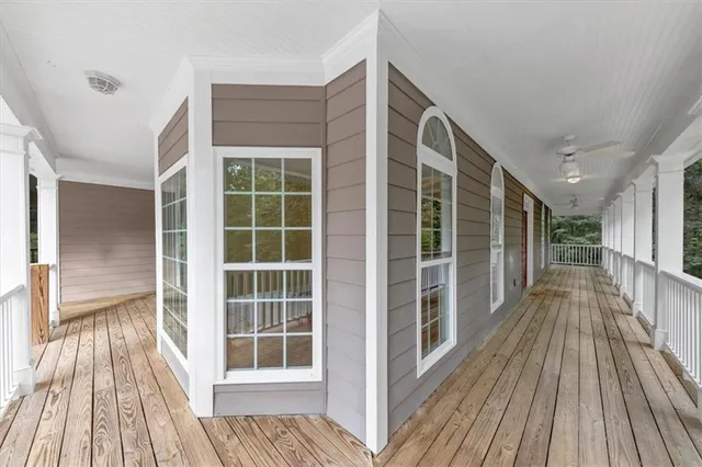 a view of a hallway with wooden floor and a ceiling fan