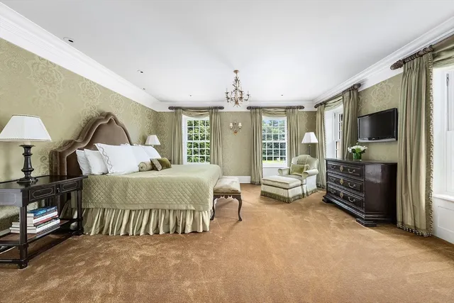 a spacious bedroom with a bed and a flat tv screen