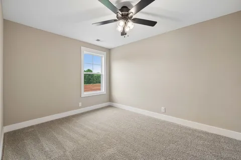 en empty room with windows and ceiling fan