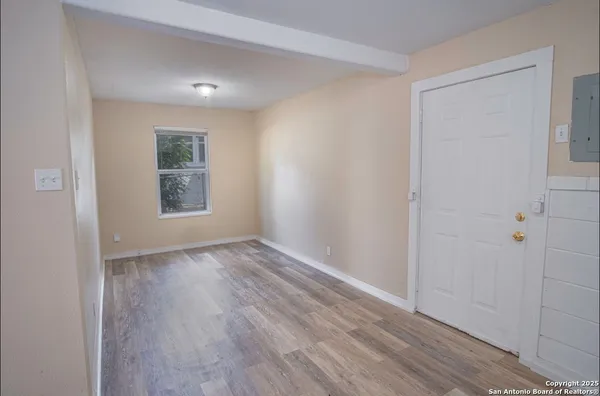 a view of an empty room with wooden floor and a window