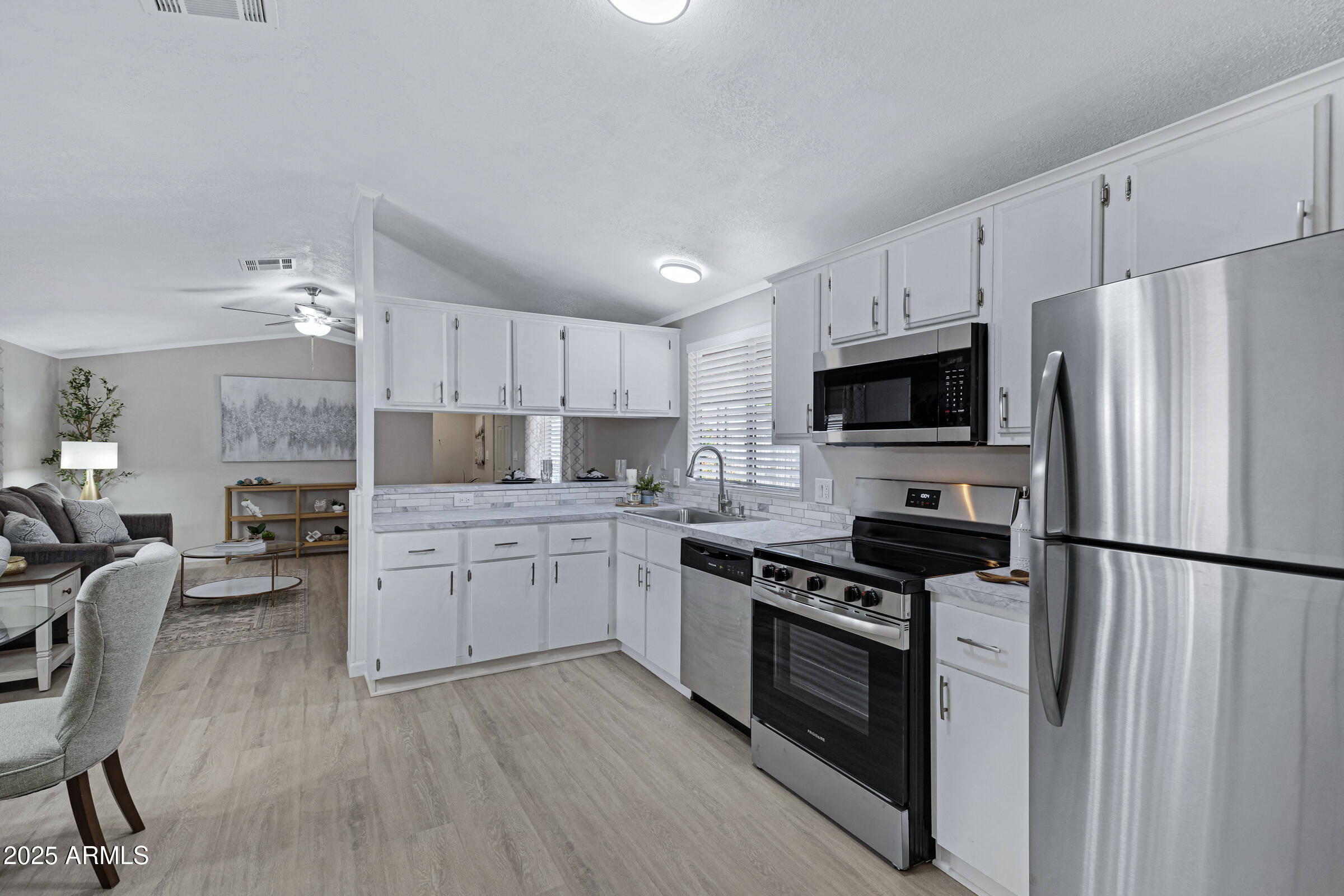 834 South Meridian Road, Unit 156 Apache Junction, AZ 85120 - Photo 3 of 20 a kitchen with granite countertop a refrigerator a stove top oven a sink dishwasher and white cabinets with wooden floor