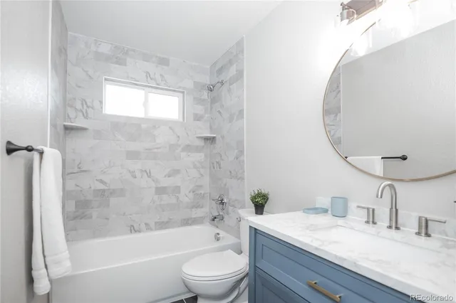 a bathroom with a granite countertop sink a toilet and shower