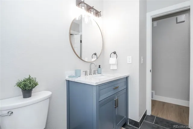 a bathroom with a granite countertop toilet a sink and a mirror