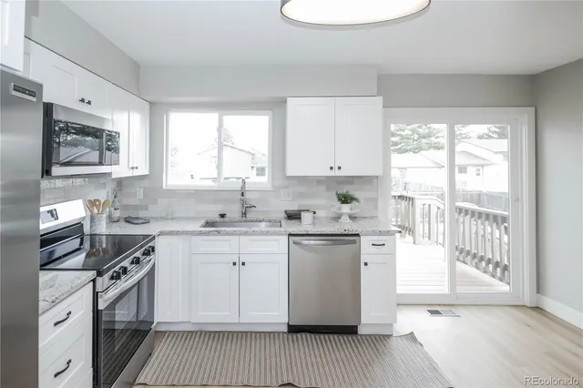 a kitchen with stainless steel appliances a stove a sink and white cabinets