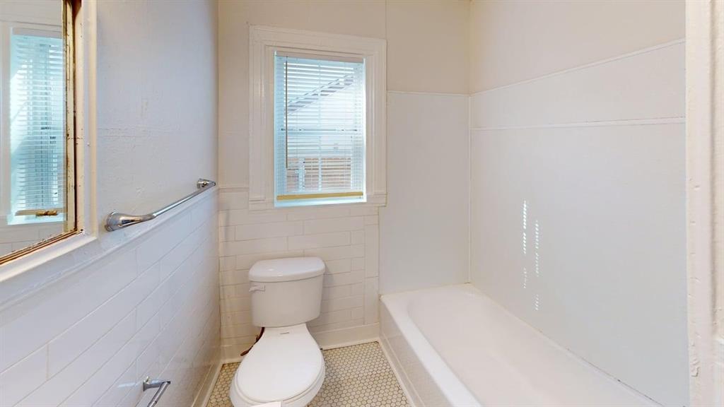 2246 Anson Road Dallas, TX 75235 - Photo 17 of 20 Bathroom featuring white subway tile wainscoting, a standard toilet, and a white bathtub with a wall surround