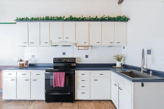 a kitchen with granite countertop white cabinets and a stove
