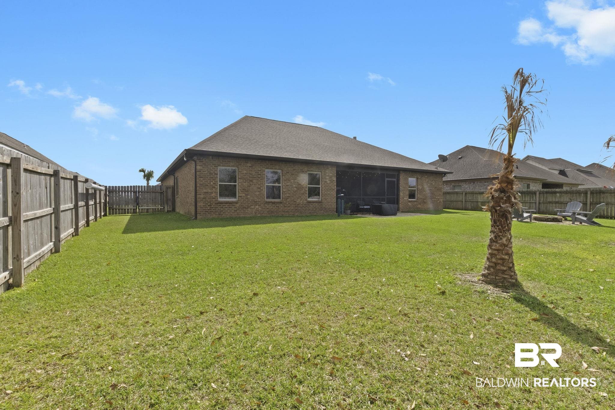 7051 Rocky Rd Loop Gulf Shores, AL 36542 - Photo 25 of 27 Back of property with a lawn, brick siding, and a fenced backyard